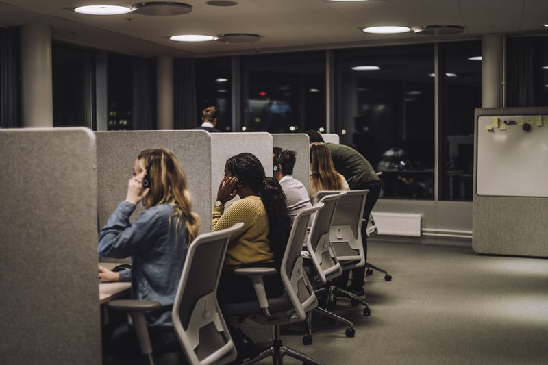 Staff in cubicles at call center making calls