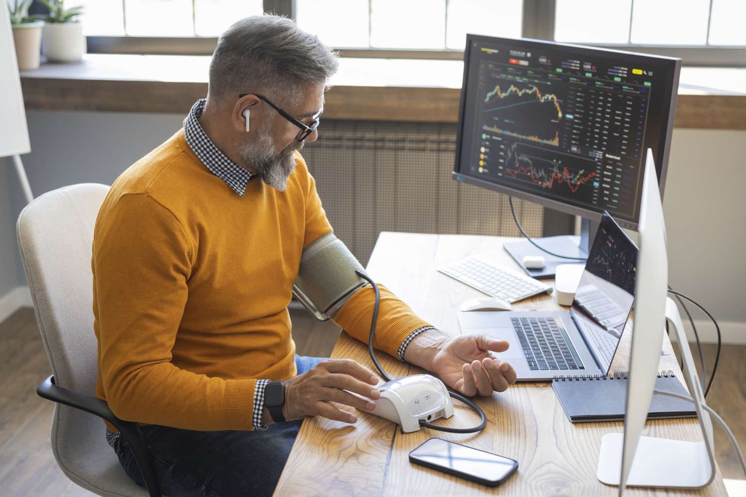 A crypto trader checks their blood pressure as they sit at a desk with computer monitors displaying various cryptocurrency charts. 