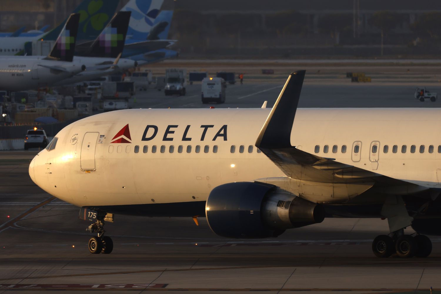A side profile of a Delta Air Lines plane is seen on an airport tarmac