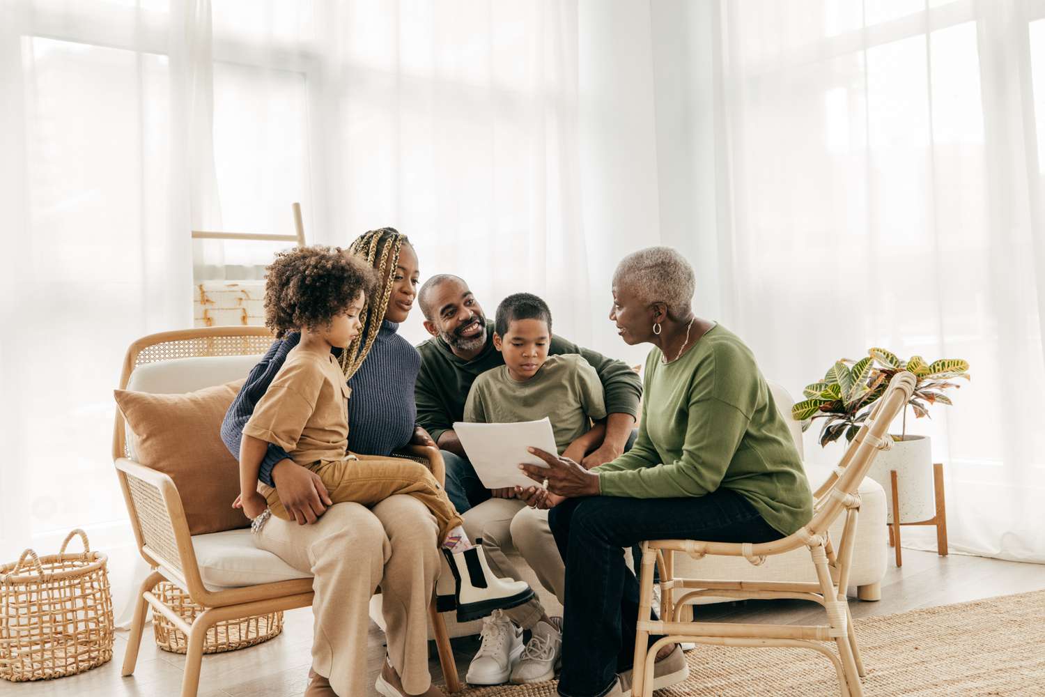 Family sitting in a living room while grandmother points to a document.