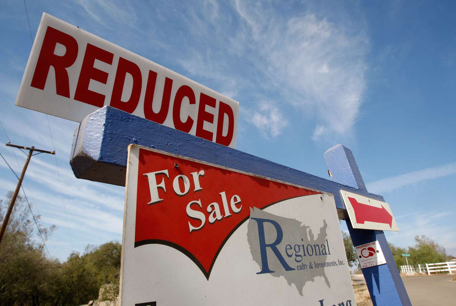 A real estate for sale sign offers a reduced price.