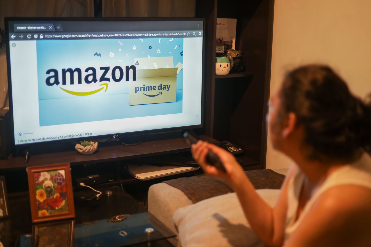 A woman looks at Amazon from her couch. 