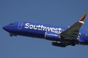 The Southwest logo is seen on the side of a blue airplane, seen in the sky.