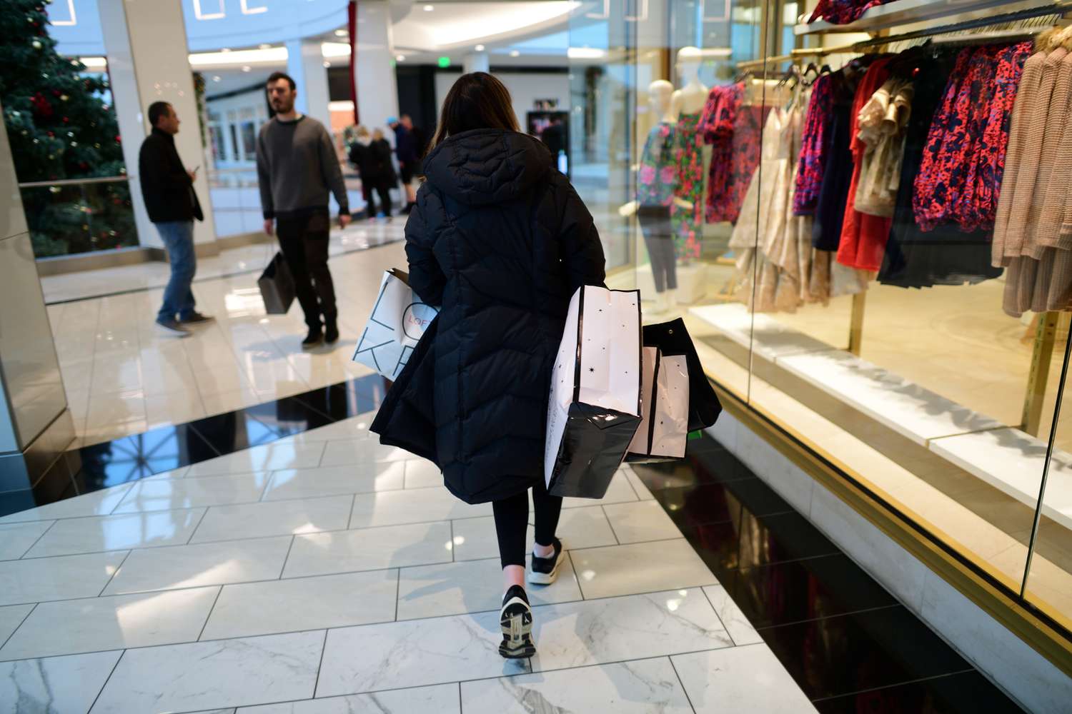 A woman carries bags of purchased merchandise in the King of Prussia Mall on Dec. 11, 2022, in King of Prussia, Pennsylvania.