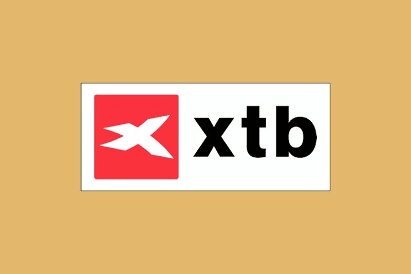Image shows XTB's logo in a white rectangle box against a mustard-colored background. 