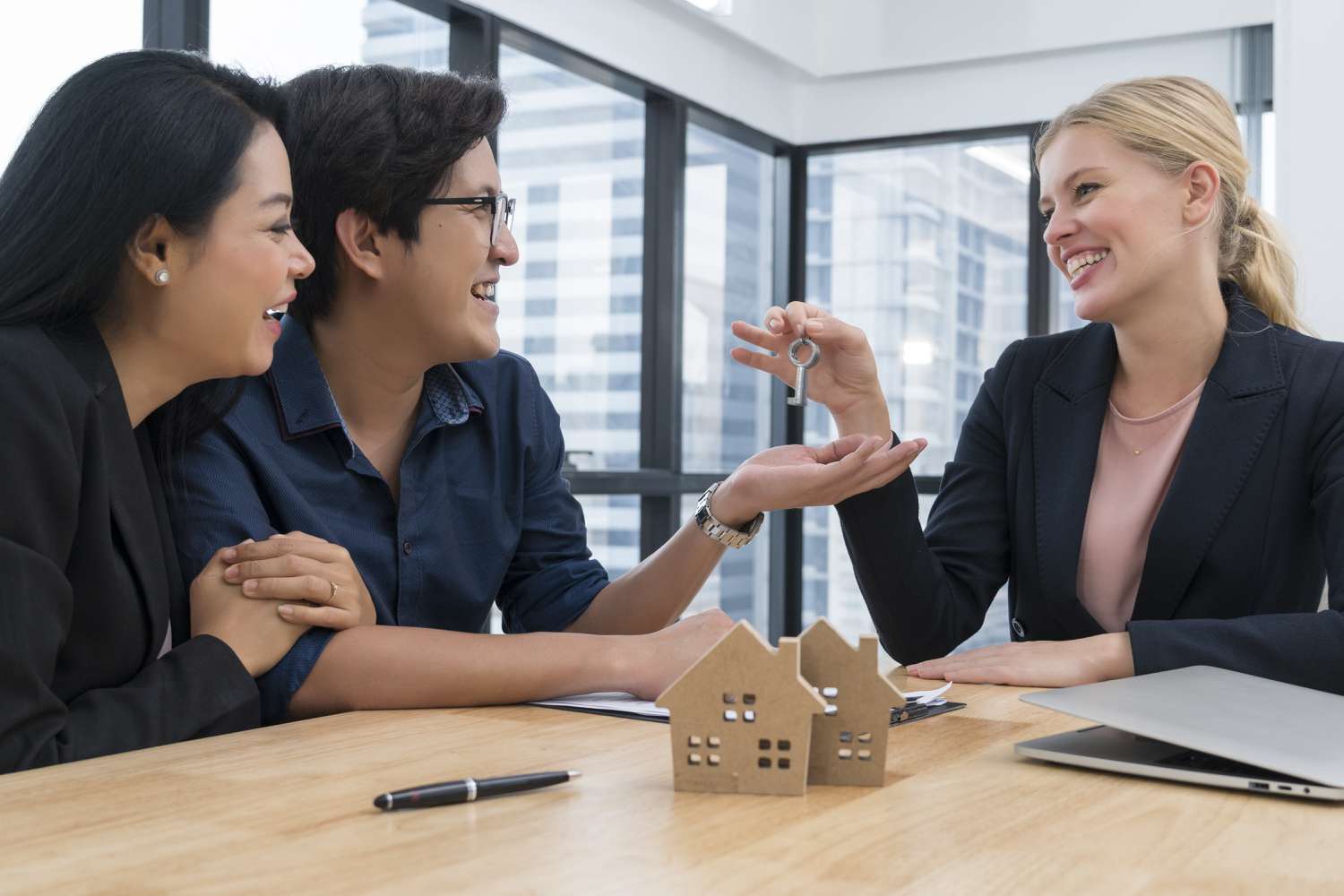 Real estate female agents deliver the new house keys to customers, happy couples after the contract is completed, rent or buy house concepts.