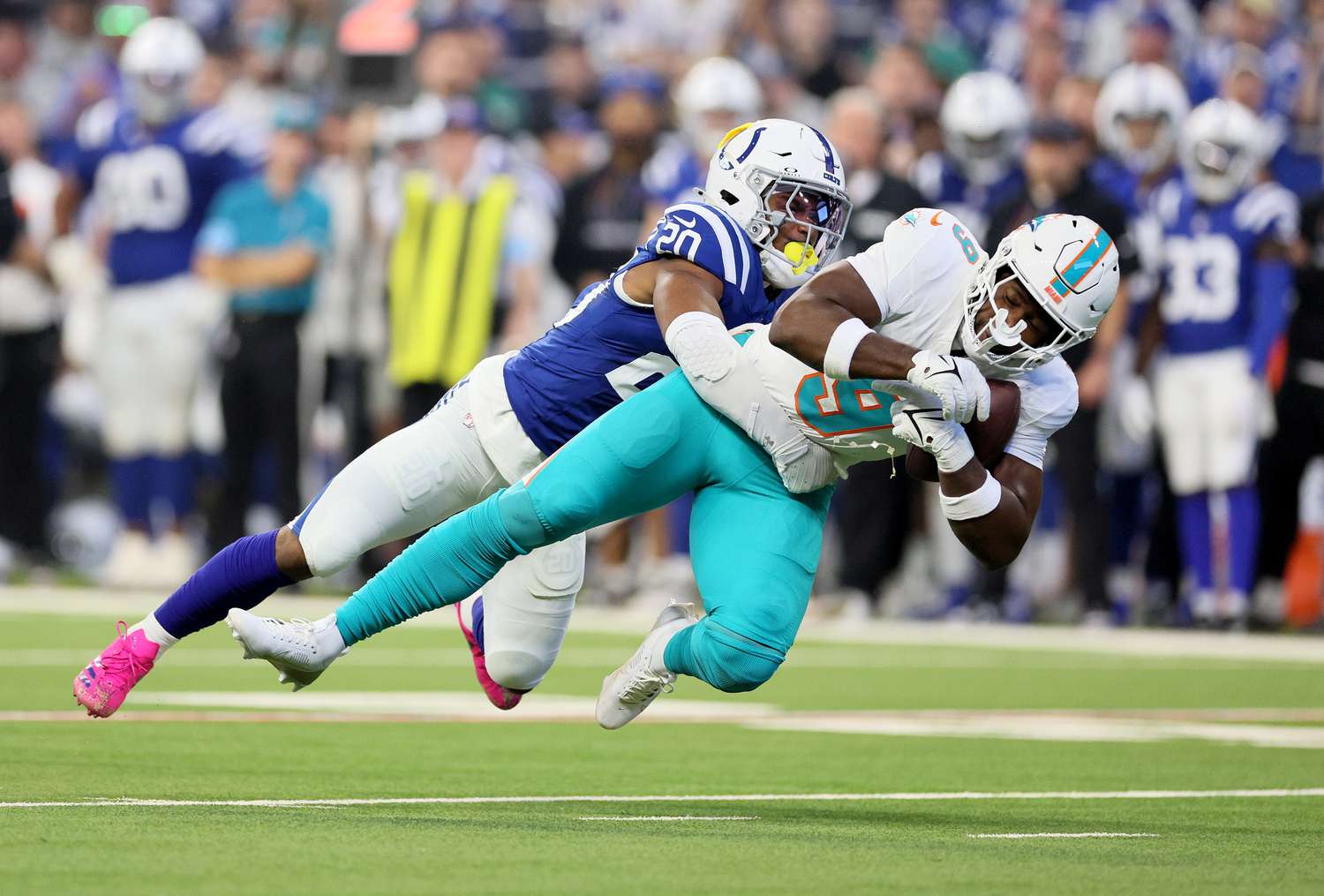 A Miami Dolphins football player is tackled by a player for the Indianapolis Colts.