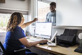 Nurse accepting payment from smiling patient at reception desk in doctor's office