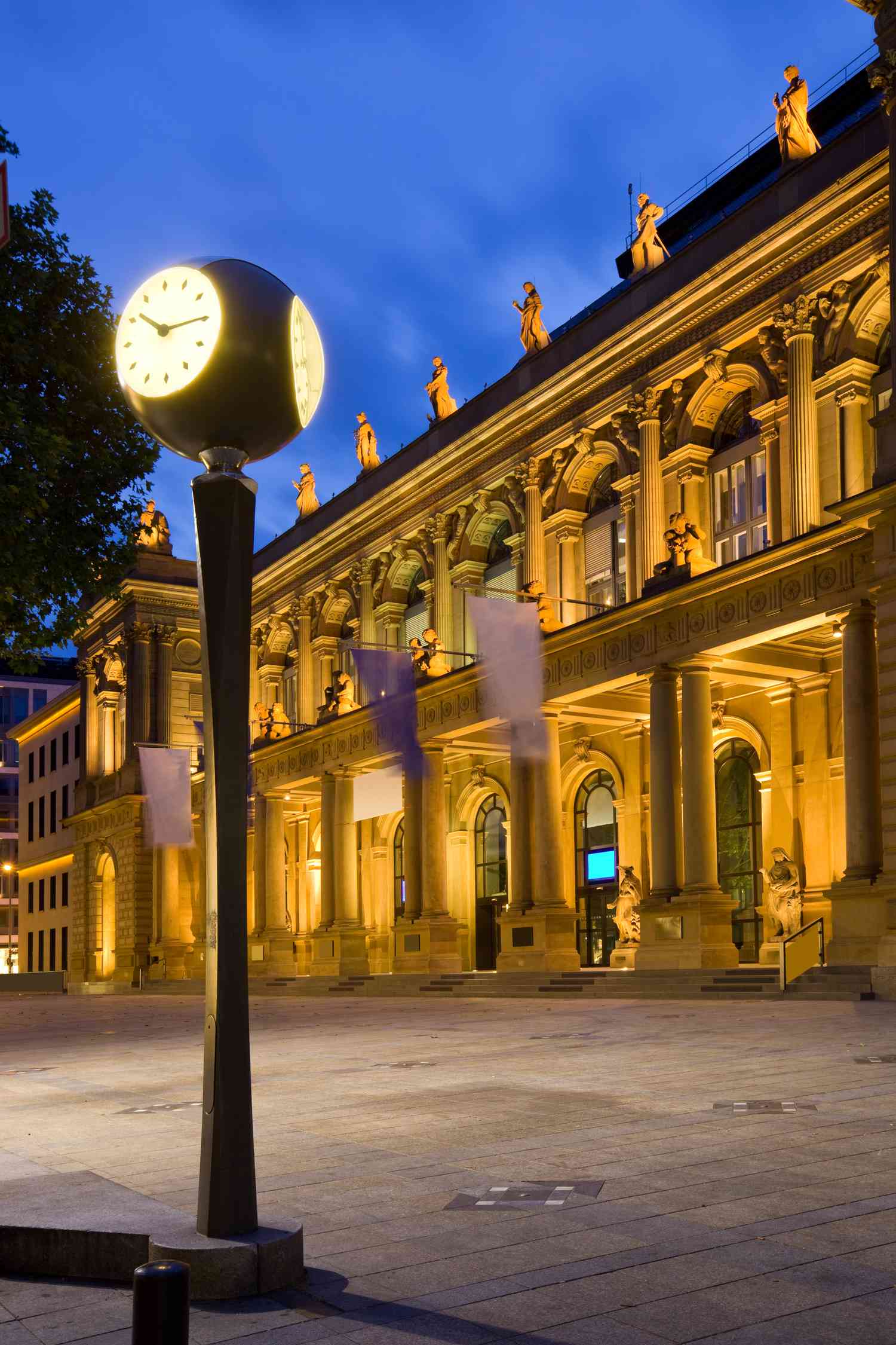 The exterior of the Frankfurt Stock Exchange and a clock at the Borsenplatz are lit for the night.