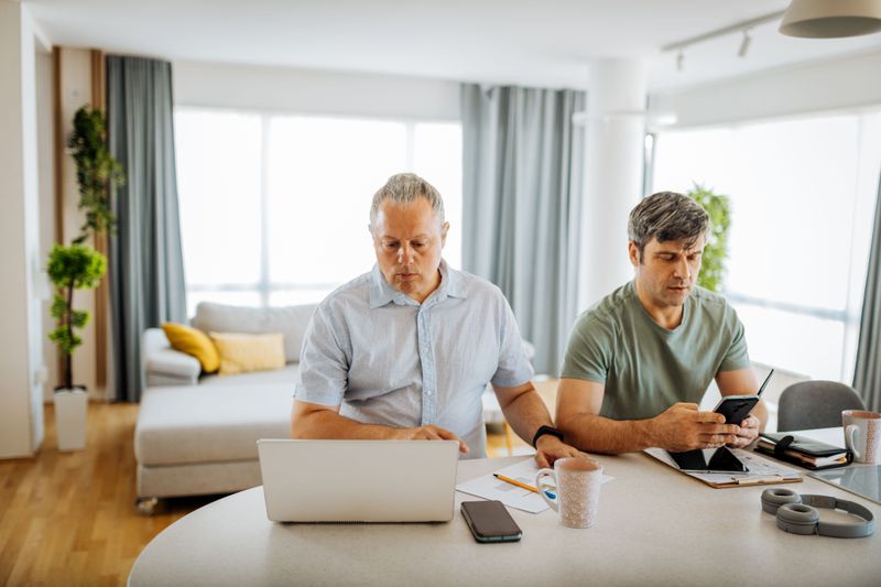 Two men working on devices at home