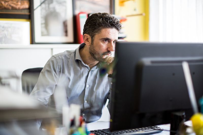 A man sitting at his desk and looking his computer.