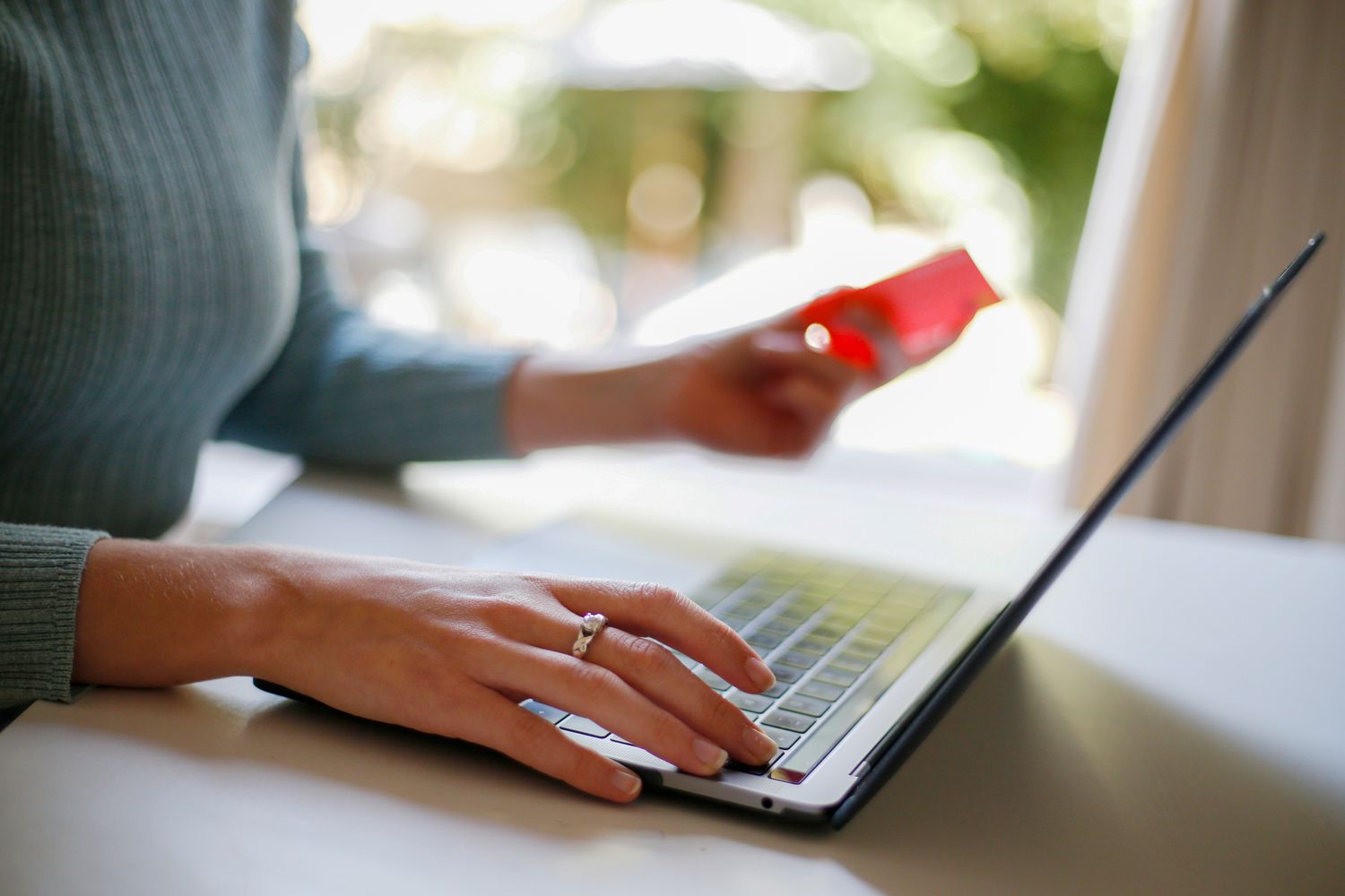 A woman uses a laptop as she holds a debit card