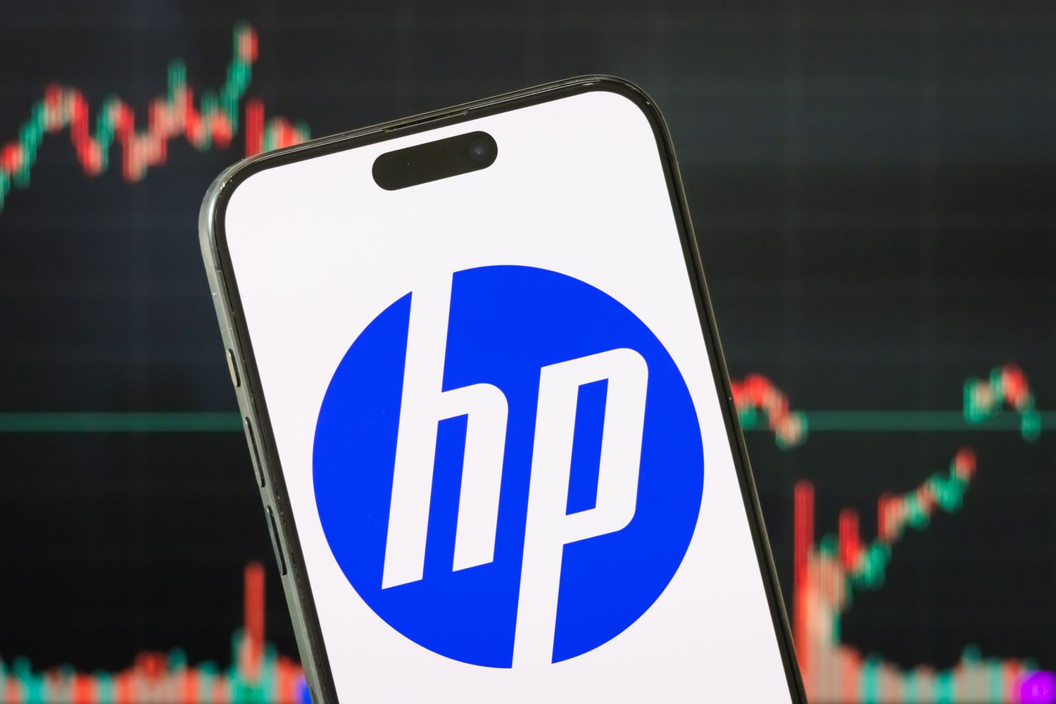 The logo of HP Inc. is displayed on a smartphone screen, with the latest stock market chart of the company in the background