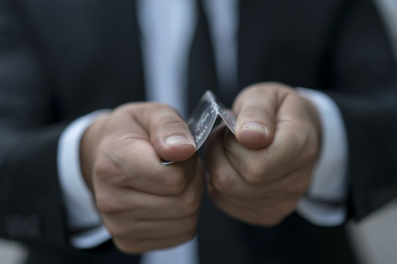 A person breaking a credit card in half to imply that the credit card is cancelled.