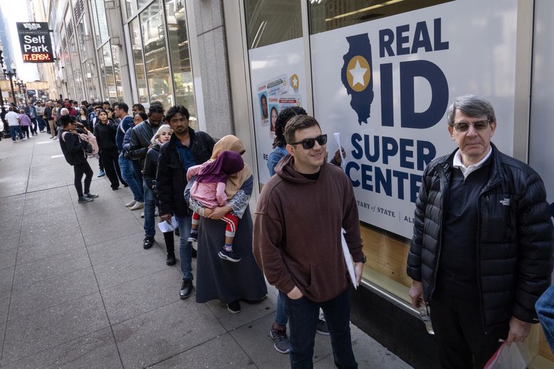 Illinois residents wait in a line that stretches nearly two blocks to enter the Real ID Super Center operated by the Secretary of State's office to apply for a Real ID on May 06, 2025 in Chicago