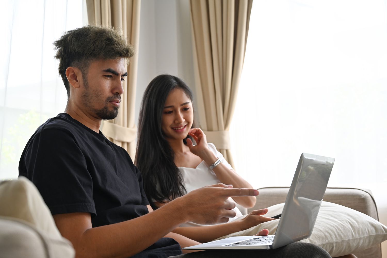 Young couple sitting on their sofa and looking at mortgage rates on a laptop