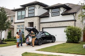A happy family in front of the house they bought with locked-in interest rate mortgage.