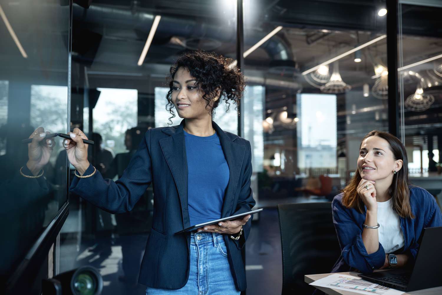 A female marketeer is on a presenting a market data on a digital display