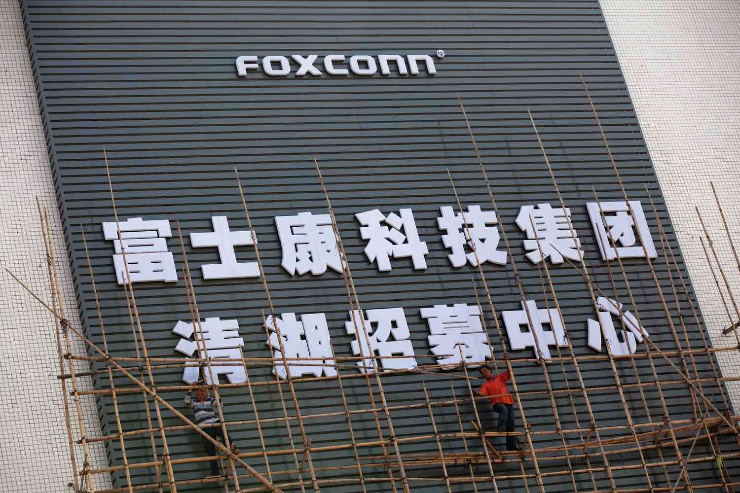 People on scaffolding in front of a building with a Foxconn logo