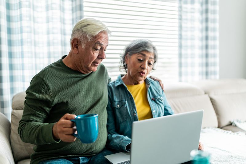 Older couple sitting on their sofa and looking at mortgage rates on a laptop