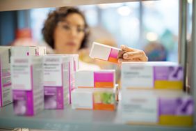 A female pharmacist checking medicines on rack.