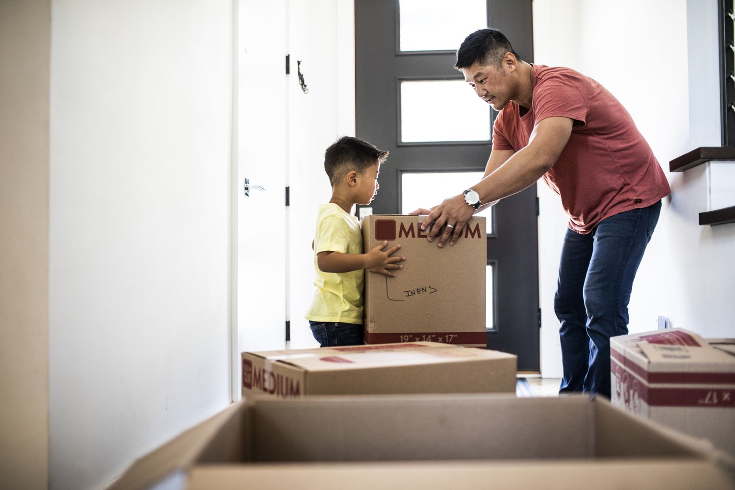 A man and a child hold moving boxes.