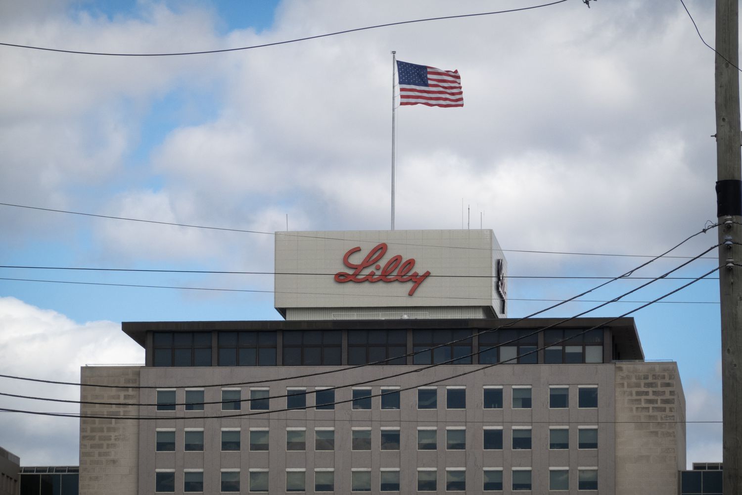 An American flag is seen above a building with the Eli Lilly logo on the side.