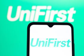 The green UniFirst logo is seen on a phone screen with a larger version in the background.