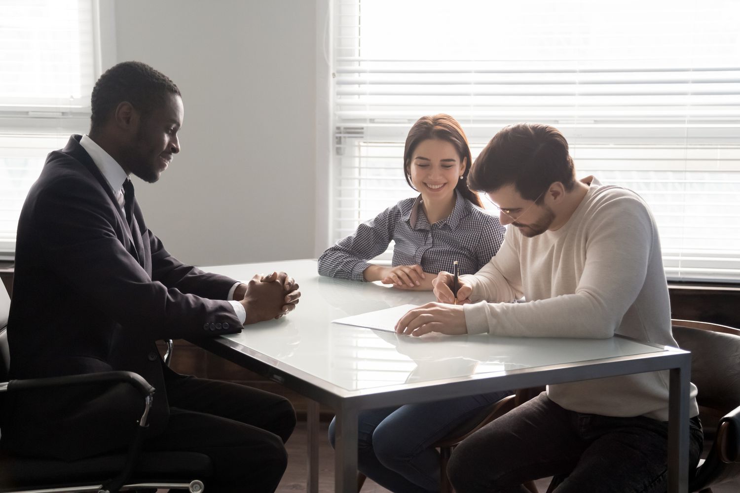 Two people meeting with a banker and signing paperwork
