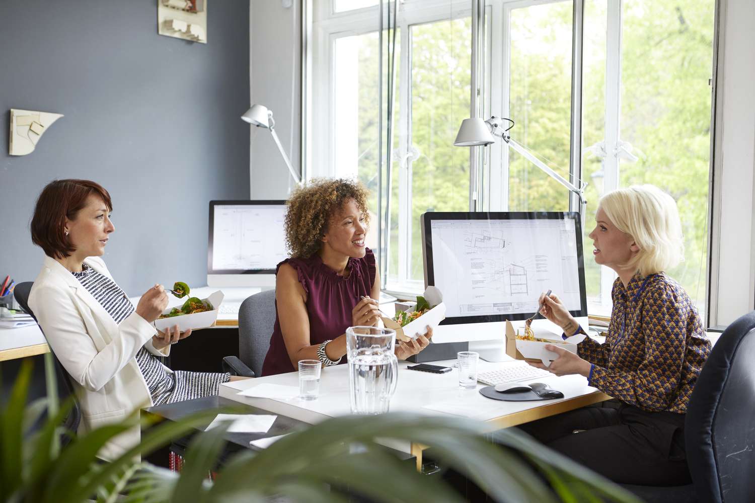 Colleagues chatting over lunch at their desk
