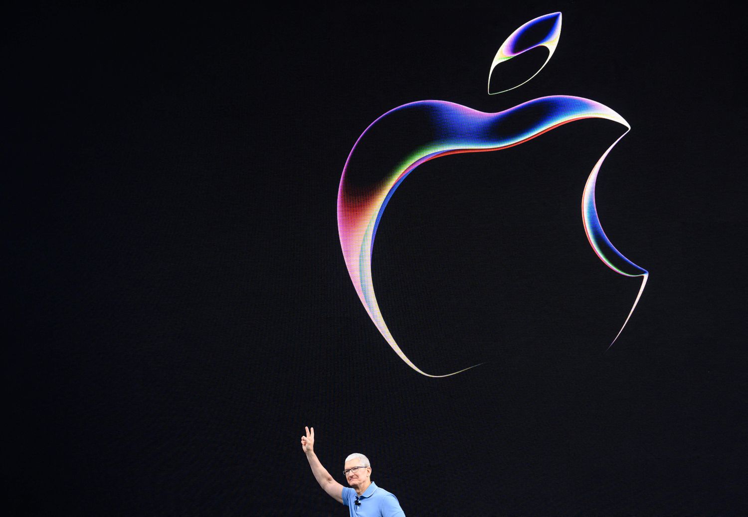 Apple CEO Tim Cook above a large Apple logo