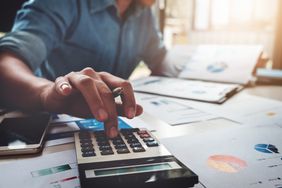 Business man using calculator analyzing costs.