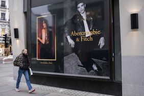 A person walks by the window displaying ads for an Abercrombie & Fitch store.