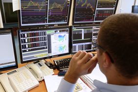 Trader looking at several monitors with stock market information