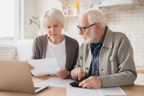 An older couple review documents at a table.