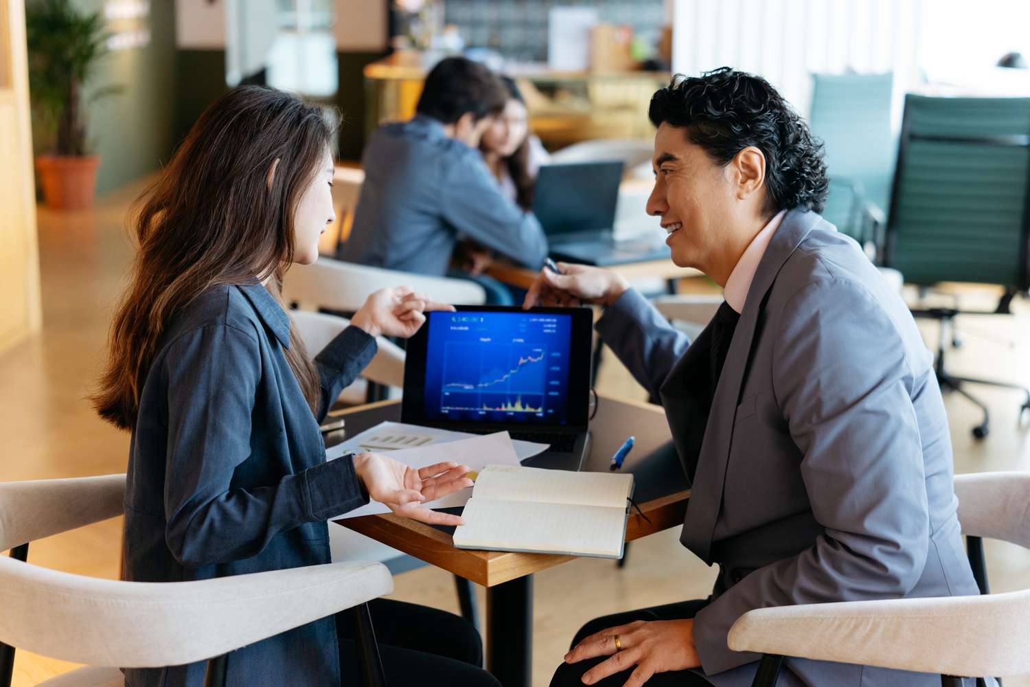 An investment advisor and client talk with a small laptop between them.