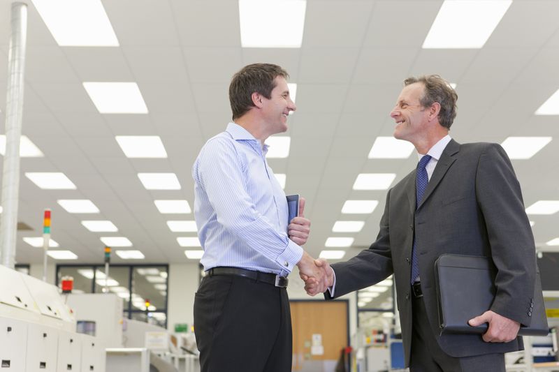 businessmen shaking hands in factory