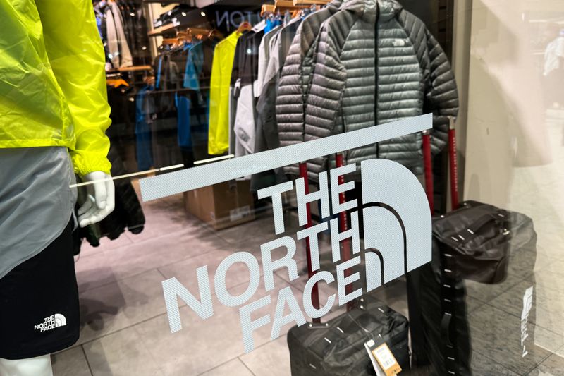 The North Face logo is seen on a window looking into a store with the company's products.