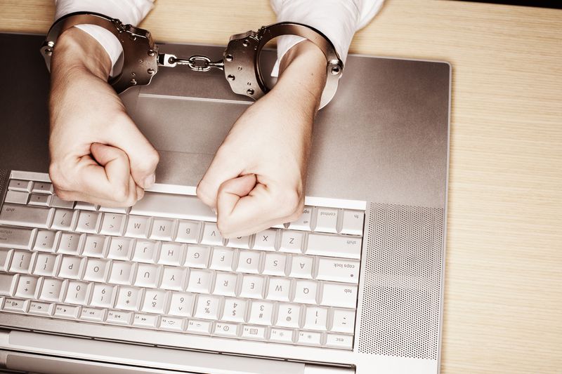 Hands in handcuffs on a laptop