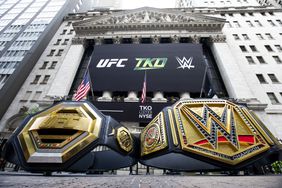 A pair of large black and gold championship belts with the UFC and WWE logo sit outside the New York Stock Exchange.