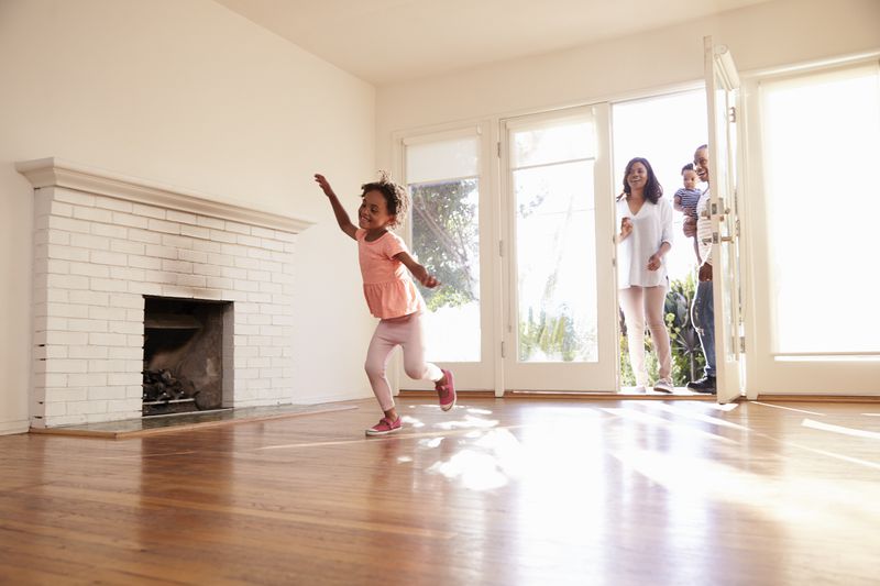 Aa family walks in the front door of a new home with a fireplace in the living room