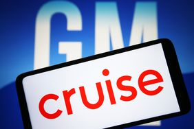 Cruise LLC logo is seen on a smartphone and General Motors Company (GM) logo on a pc screen