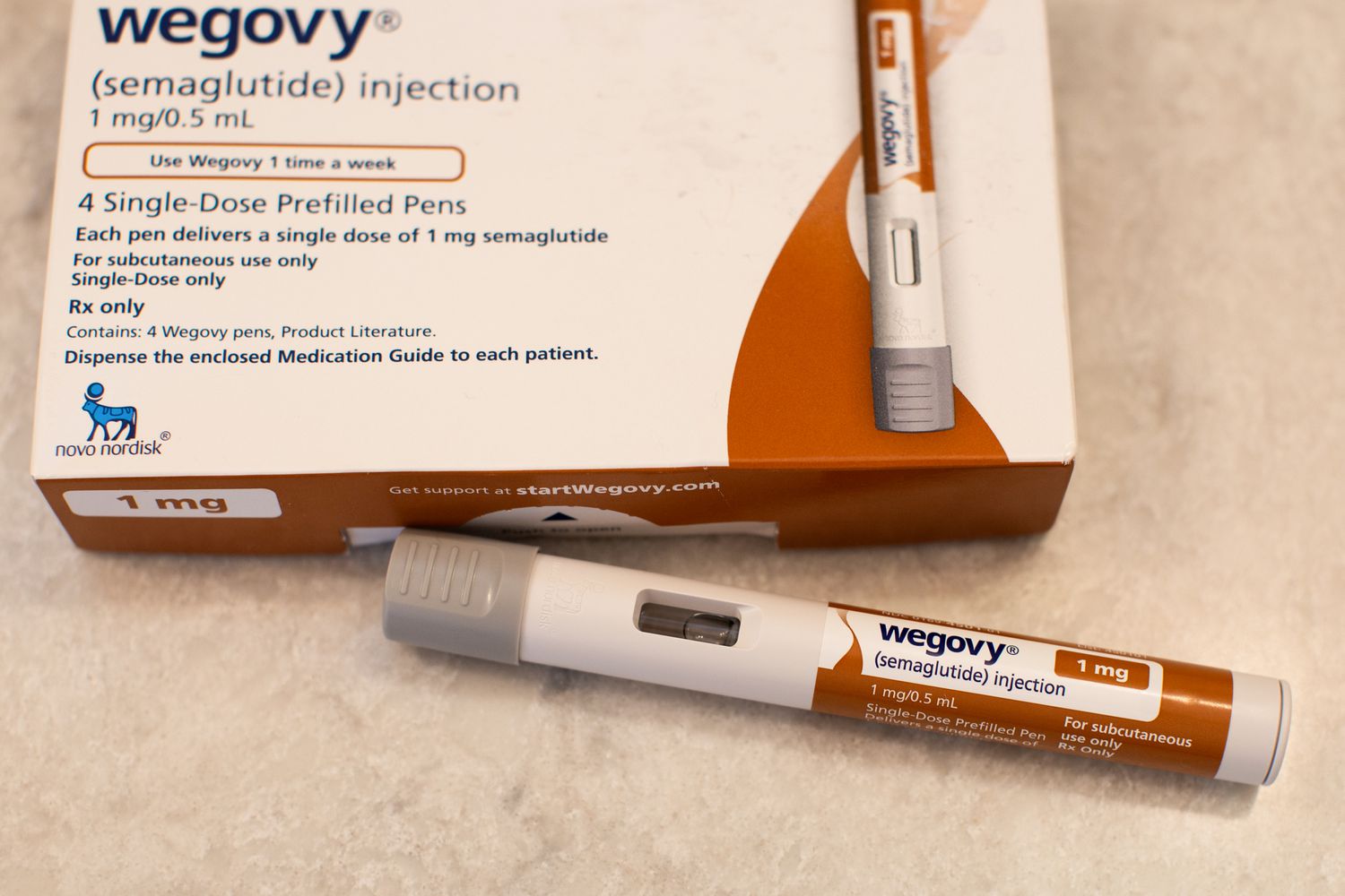 A brown and white Wegovy pen sits on a table next to a box for the drug.