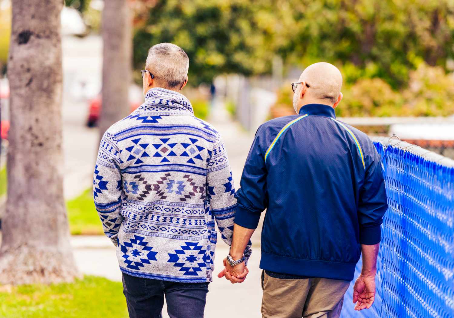 A rear view of two gay men in their 40s walking on a residential street in Los Angeles, California