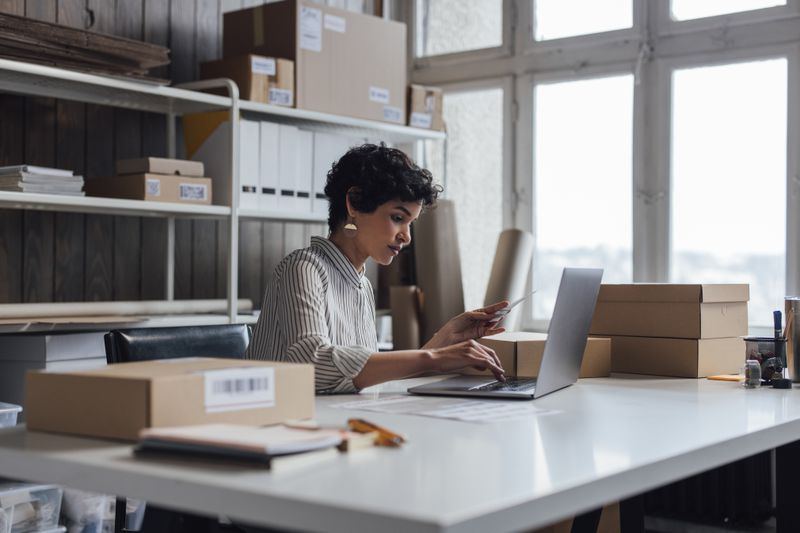 A young small business owner using her laptop computer to check the customer's order details on her web site
