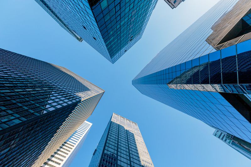 looking up at skyscrapers in manhattan with a blue sky