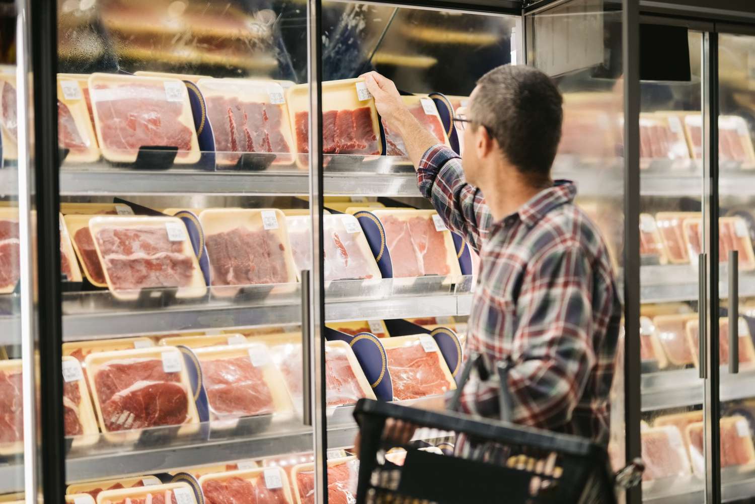 A man looks at meat in a store.