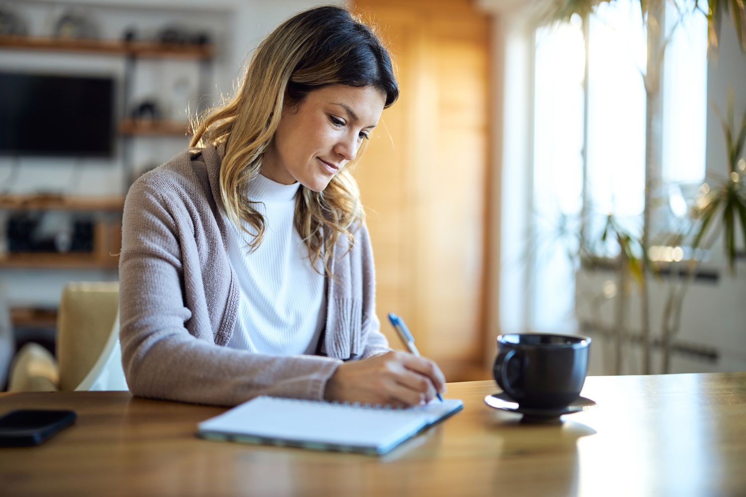 A woman signs a check at a desk.