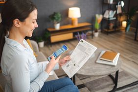 Young woman paying home financial bill with QR code scanner on her phon