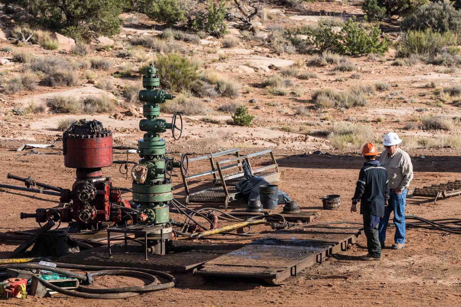 Service crew by a partially disassembled blowout preventer on an oil well head undergoing intervention..